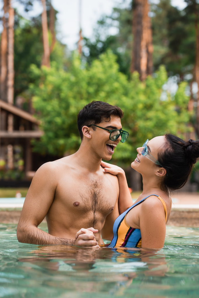 Весела пара тримає руки, стоячи в басейні
  - Фото, зображення