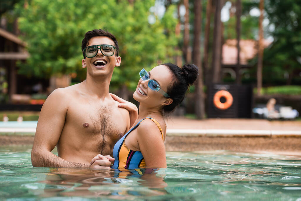 Smiling woman holding hand of boyfriend in swimming pool  - Photo, Image