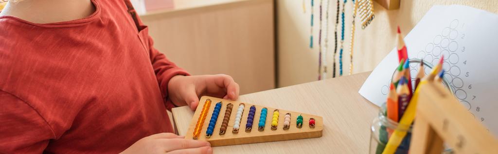 vista ritagliata del ragazzo che gioca con perline colorate gioco nella scuola montessori, banner - Foto, immagini