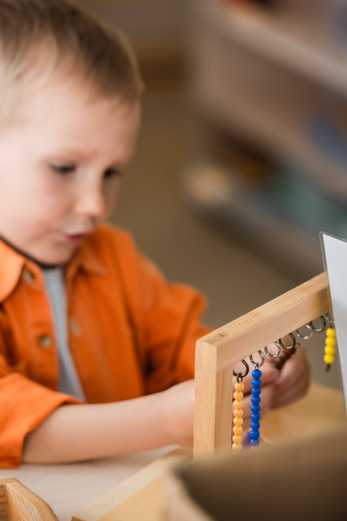 menino borrado jogando jogo de contas de madeira na escola montessori - Foto, Imagem