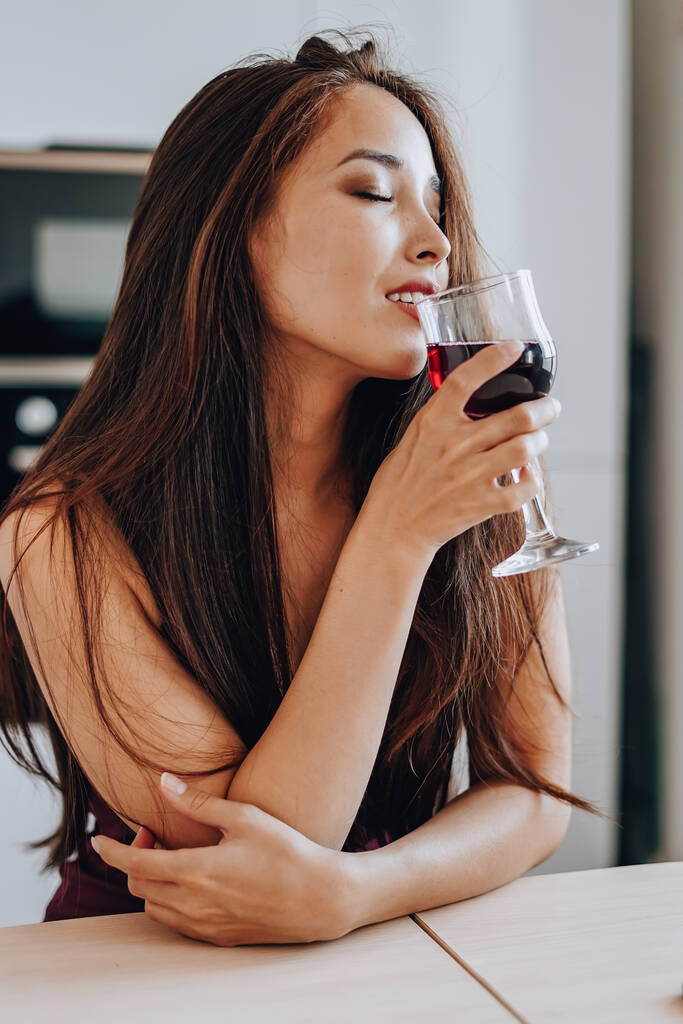 mujer asiática bebiendo vino en la cocina en casa - Foto, Imagen