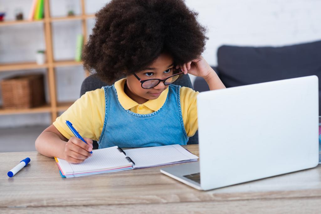 Niño afroamericano mirando a la computadora portátil durante la educación en casa  - Foto, imagen