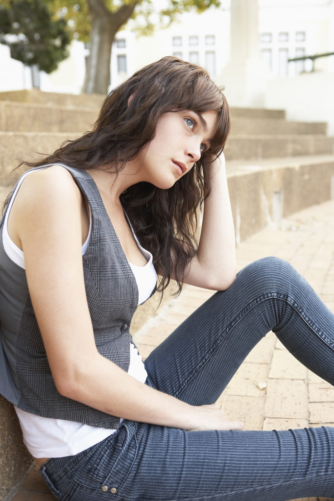 Onneton nainen teini-ikäinen opiskelija istuu ulkopuolella College Steps
 - Valokuva, kuva
