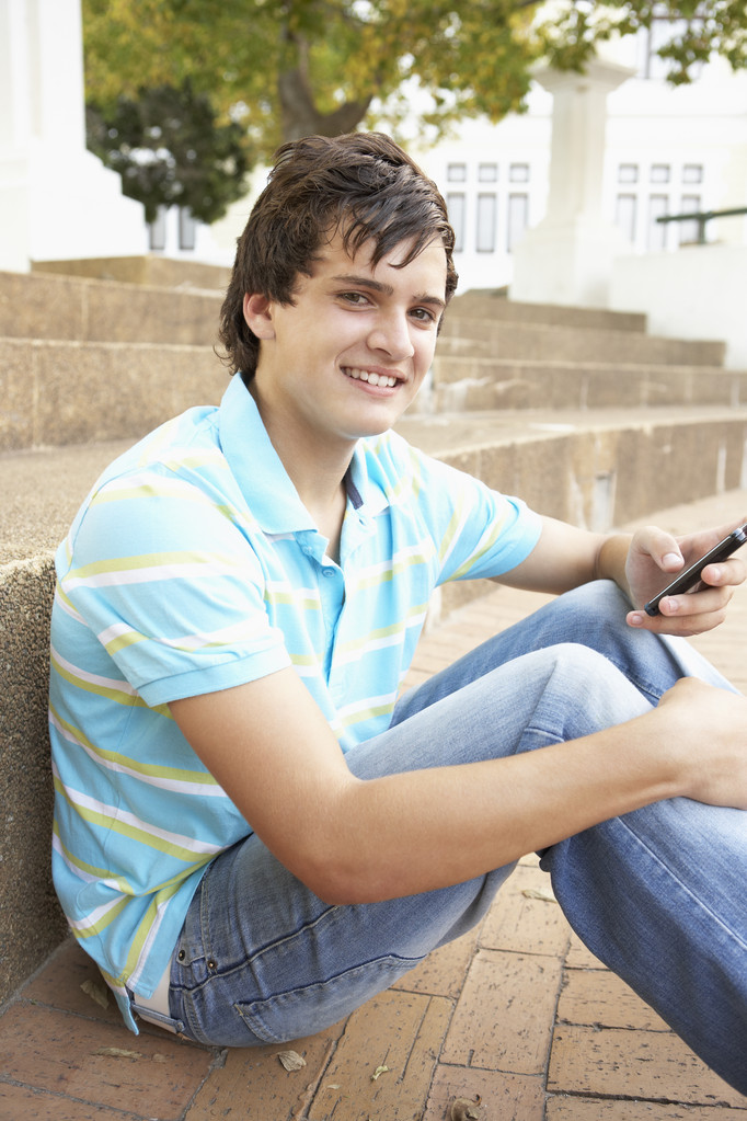 maschio adolescente studente seduta al di fuori su college passi utilizzando mobi
 - Foto, immagini
