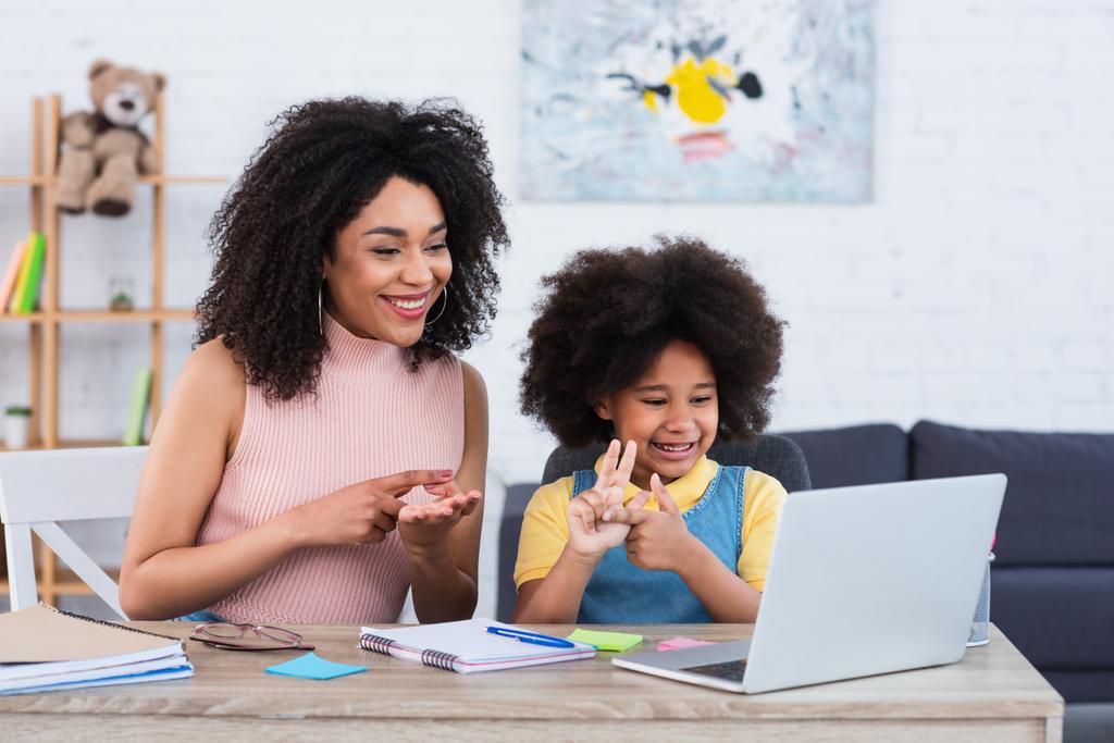 Fröhliche afrikanisch-amerikanische Mutter und Kind beim E-Learning am heimischen Laptop an den Fingern abzählen  - Foto, Bild