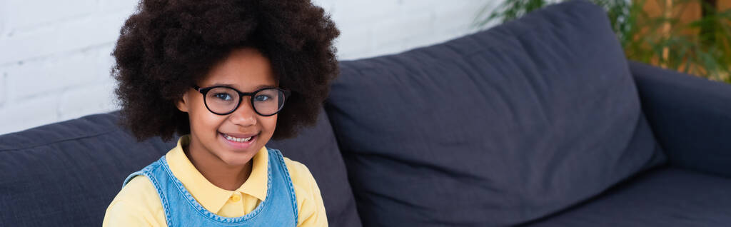 Afrikaans Amerikaans kind in bril kijkend naar camera op bank, banner  - Foto, afbeelding