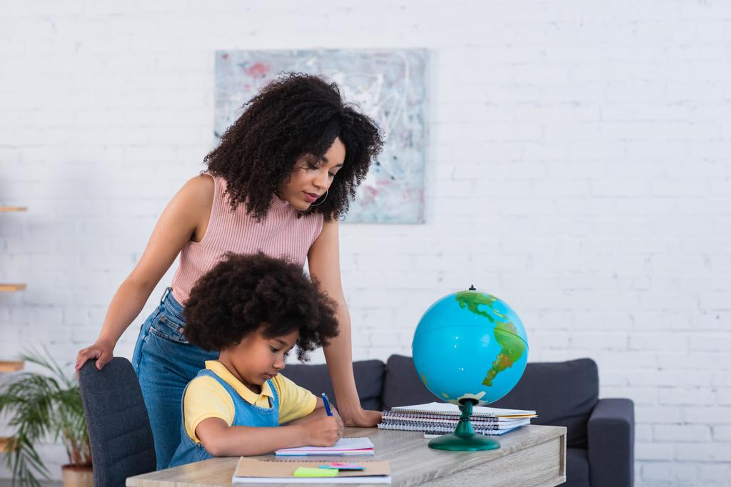 Afrikai amerikai szülő segít lánya iskolai munka otthon  - Fotó, kép
