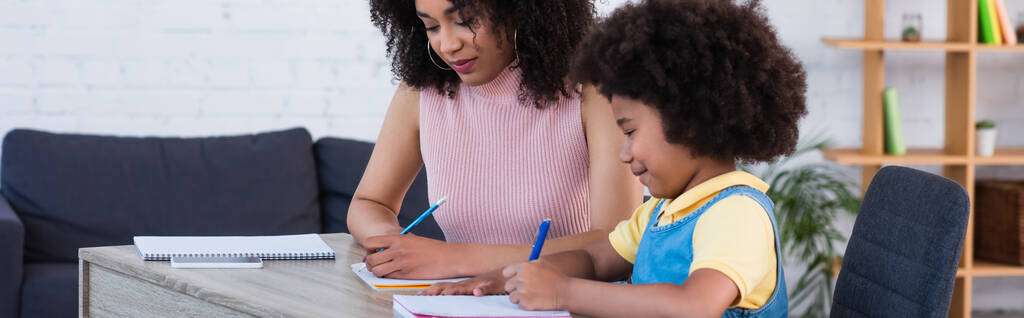 Sorrindo menina afro-americana fazendo trabalhos escolares com a mãe, banner  - Foto, Imagem