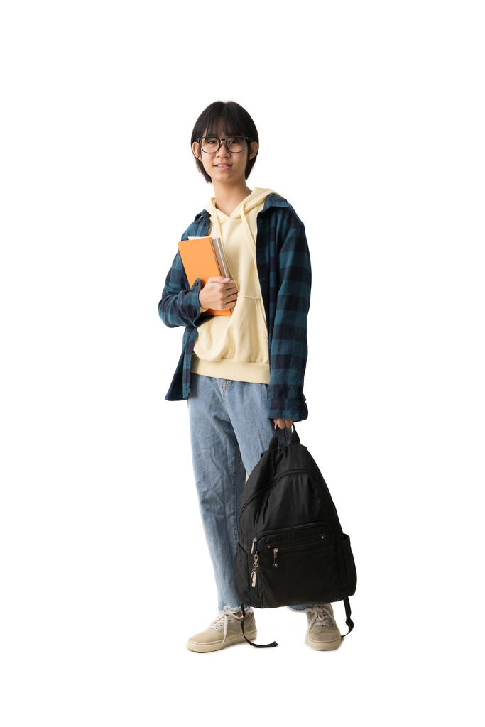 Щаслива дівчина азіатського підлітка тримає книжку й носить рюкзак, відокремлений на білому фоні. - Фото, зображення