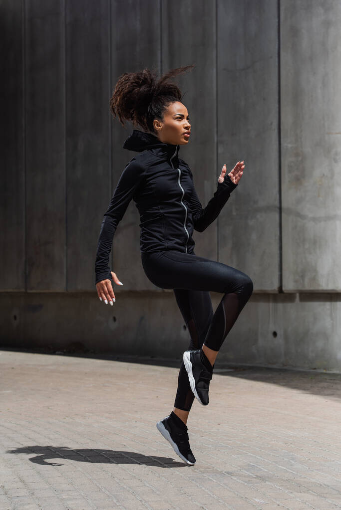 Side view of pretty african american sportswoman training on urban street  - Photo, Image
