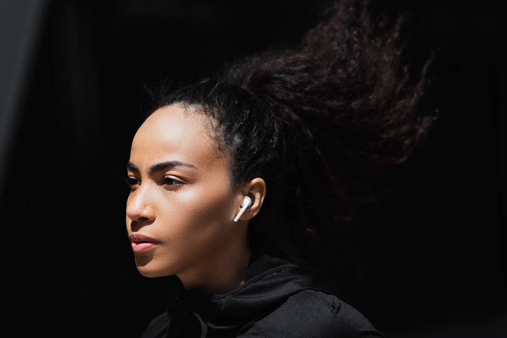 Fiatal afro-amerikai sportnő vezeték nélküli fülhallgatóval a szabadban  - Fotó, kép