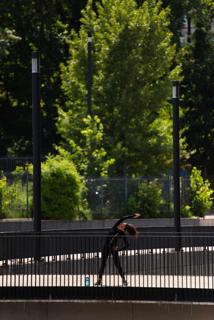 Nuori afrikkalainen amerikkalainen urheilija taivutus harjoitellessaan sillalla  - Valokuva, kuva