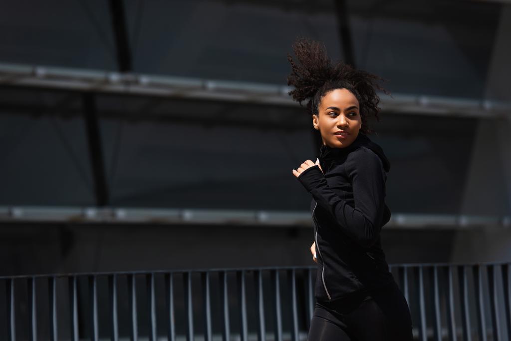 Bastante afroamericano corredor en ropa deportiva negro corriendo en la calle urbana  - Foto, imagen