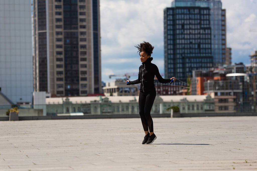 Deportista afroamericana haciendo ejercicio con saltar la cuerda en la calle urbana  - Foto, Imagen
