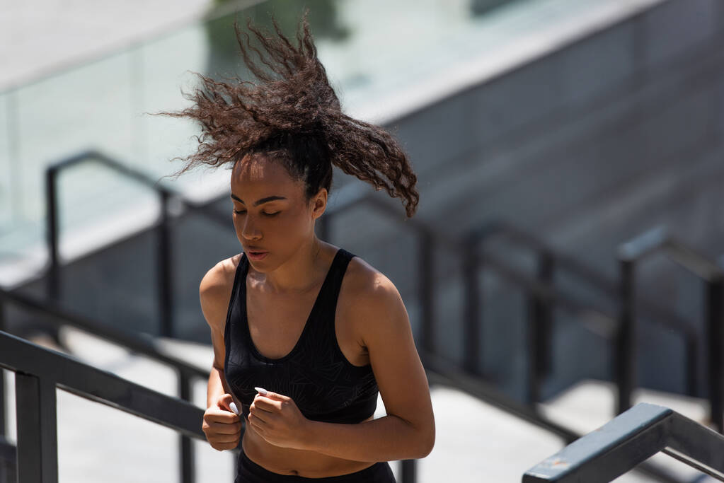 African american sportswoman jogging on stairs outdoors  - Photo, Image