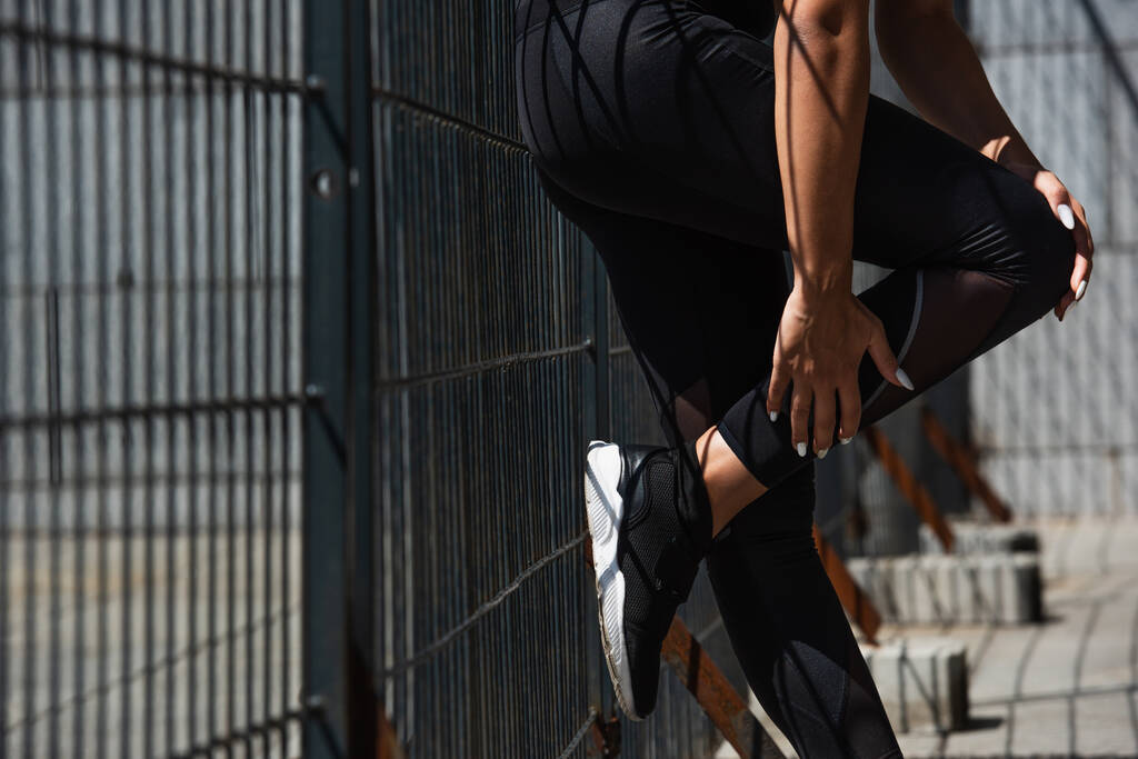 Vágott kilátás afro-amerikai sportnő áll kerítés közelében  - Fotó, kép