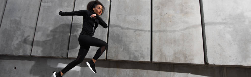 Africká americká sportovkyně běžící poblíž budovy venku, prapor  - Fotografie, Obrázek