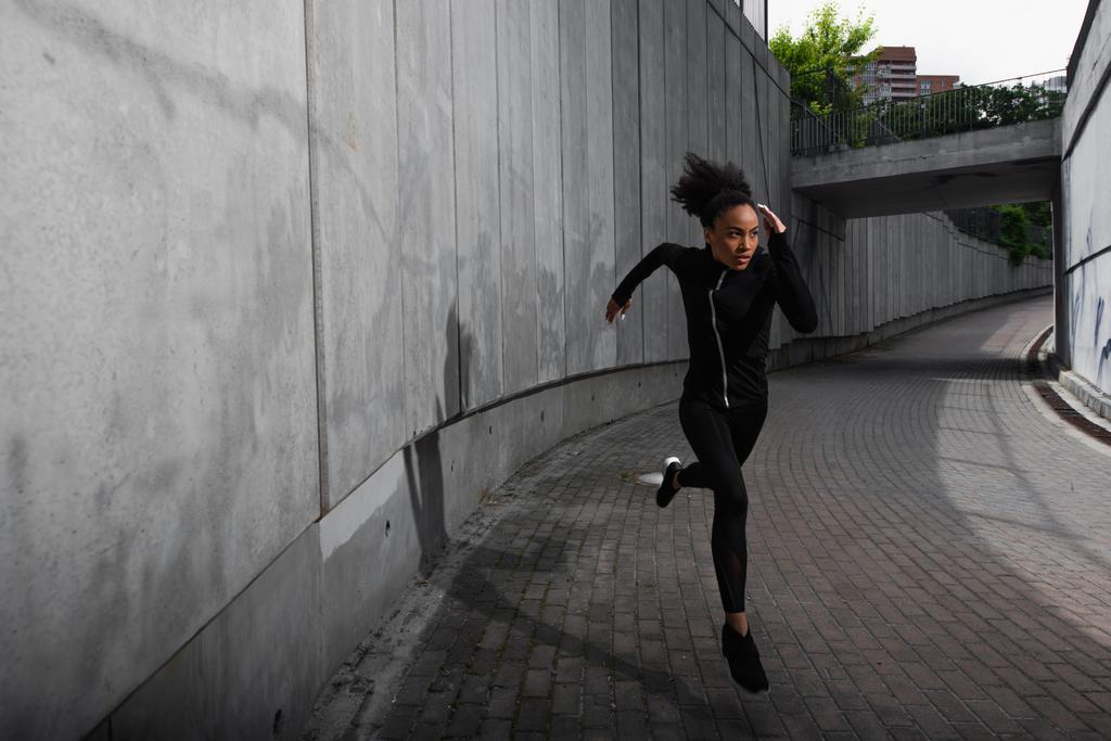 Focused african american sportswoman training while running outdoors  - Photo, Image