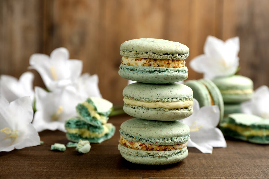 Delicious macarons and flowers on wooden table - Photo, Image