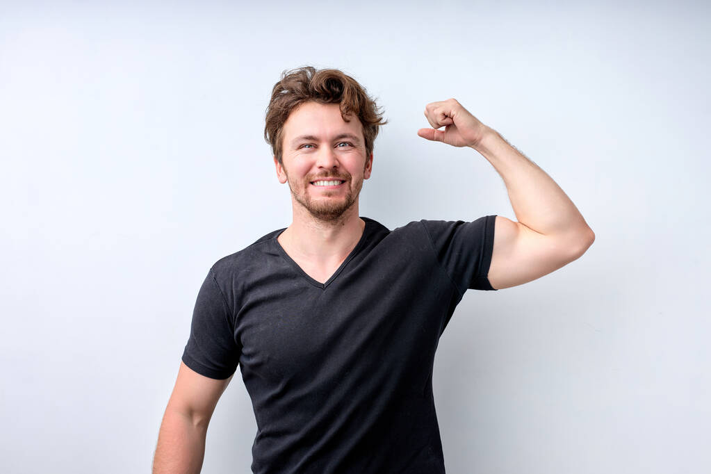 Positivo Forte jovem poderoso levanta os braços e mostra bíceps - Foto, Imagem