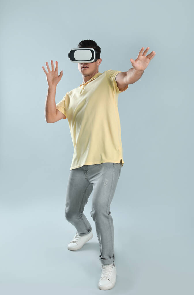 Homem usando fones de ouvido de realidade virtual em fundo cinza - Foto, Imagem