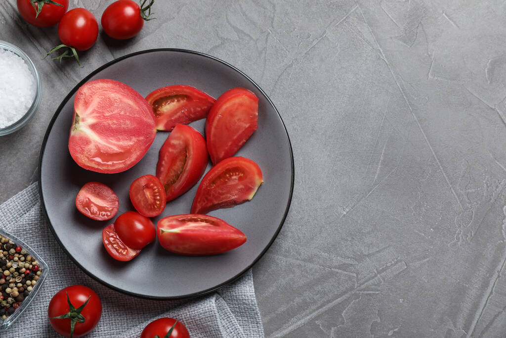 Deliziosi pomodori freschi su tavola grigia, posa piatta. Spazio per testo - Foto, immagini