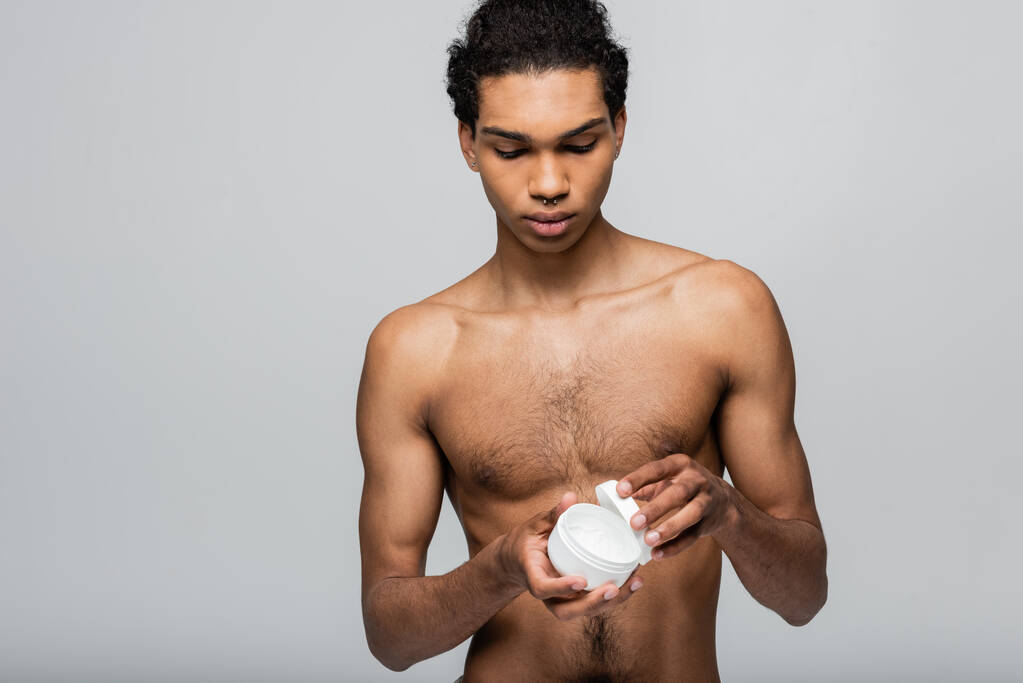 sin camisa afroamericano chico apertura contenedor con crema cosmética aislado en gris - Foto, imagen