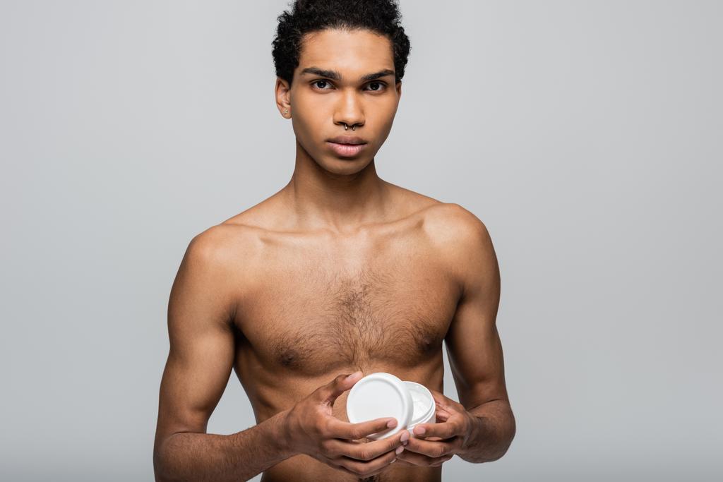 bez košile africký Američan chlap otevření kosmetické krém při pohledu na kameru izolované na šedé - Fotografie, Obrázek