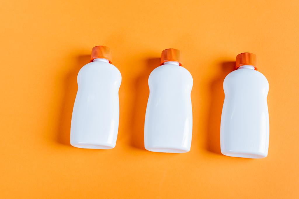 top view of white bottles with sunscreen on orange background - Foto, Imagem