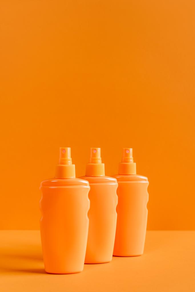 спрей бутылки солнцезащитного крема изолированы на оранжевый - Фото, изображение