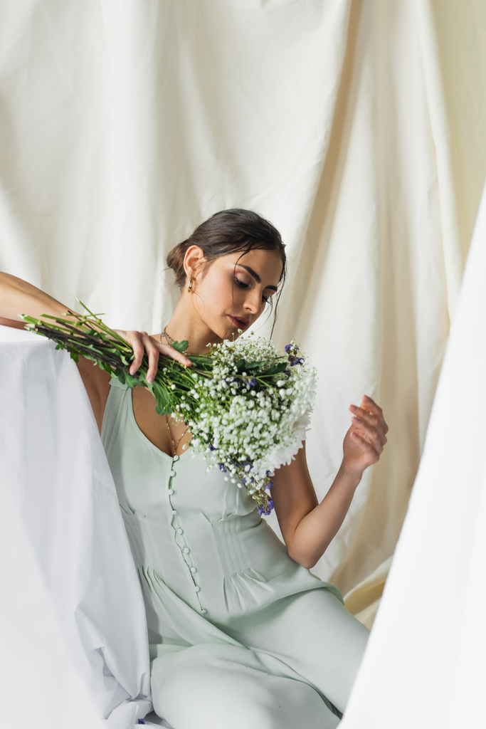 pretty woman looking at bouquet of flowers on white - Photo, Image