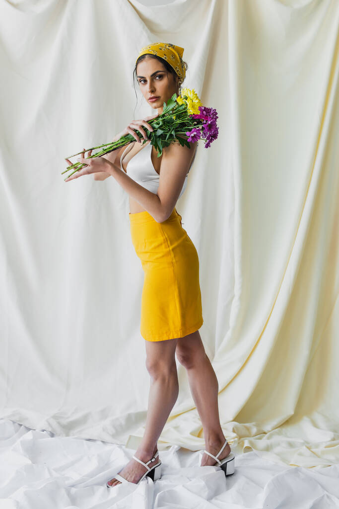volle Länge der hübschen Frau in gelbem Kopftuch mit Blumen auf weißem Hintergrund - Foto, Bild