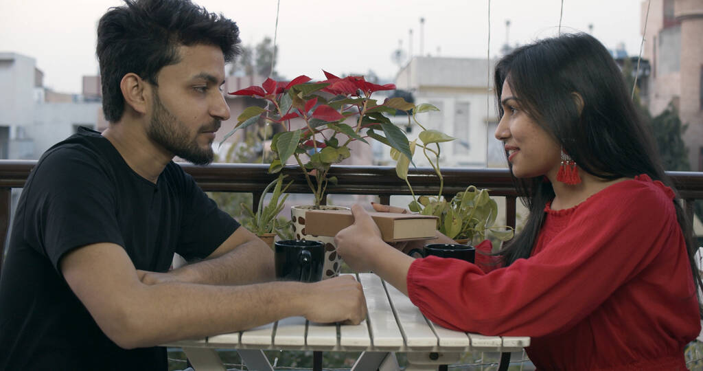 Un jeune couple indien échangeant des cadeaux pour la Saint Valentin dans un restaurant - Photo, image
