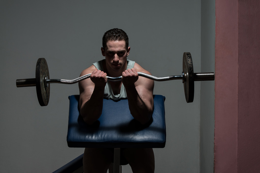 muž v tělocvičně cvičení biceps s činka - Fotografie, Obrázek