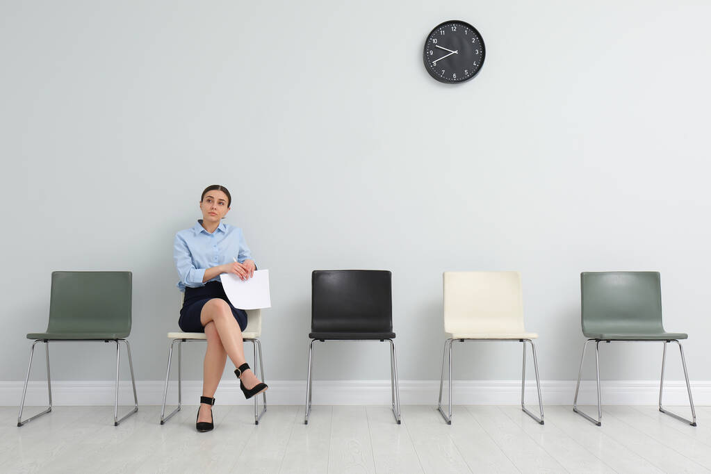 Jeune femme avec des papiers en attente d'un entretien d'embauche dans la salle de bureau - Photo, image