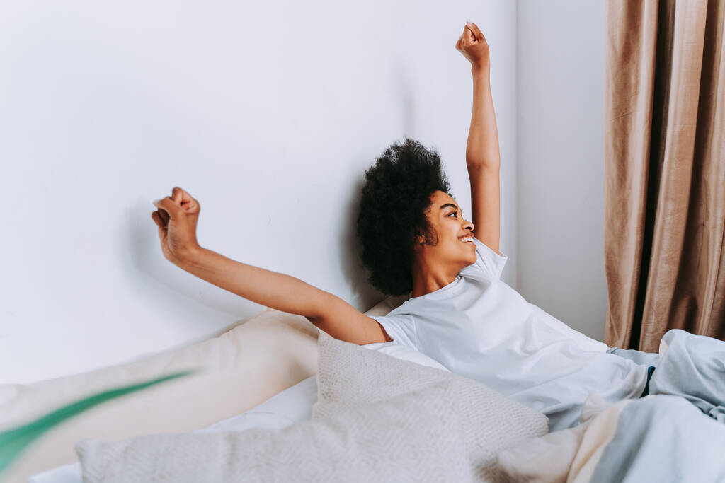 Menina afro-americana descansando na cama em casa - Mulher bonita relaxando em casa - Foto, Imagem