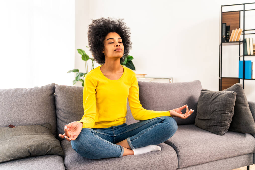 Afro fille américaine se détendre à la maison avec méditation de yoga - Belle fille noire méditant dans le salon - Photo, image