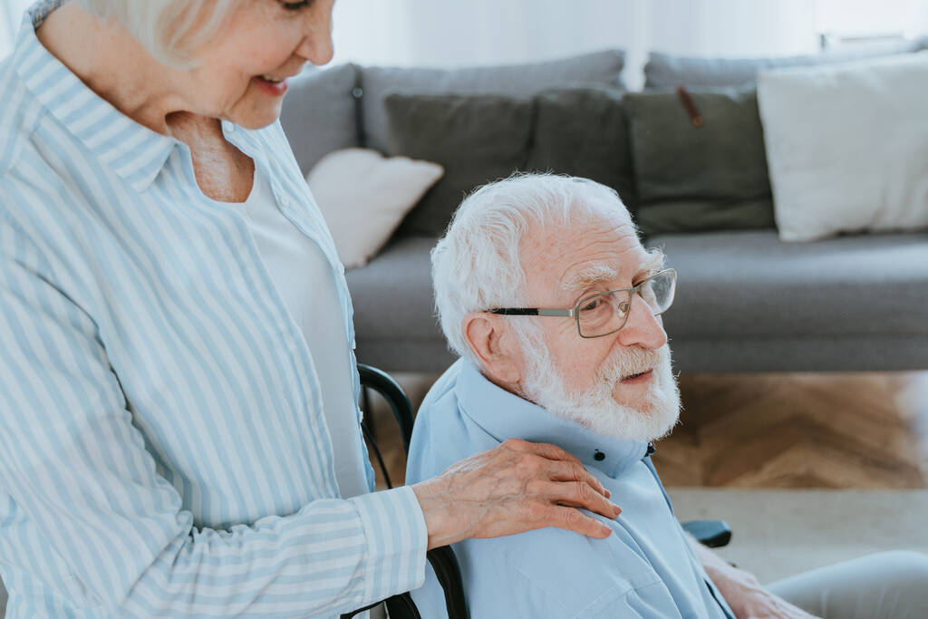 Homem idoso com deficiência na cadeira de rodas - Casal sênior em casa, parceiro que volta do hospital em convalescença - Foto, Imagem