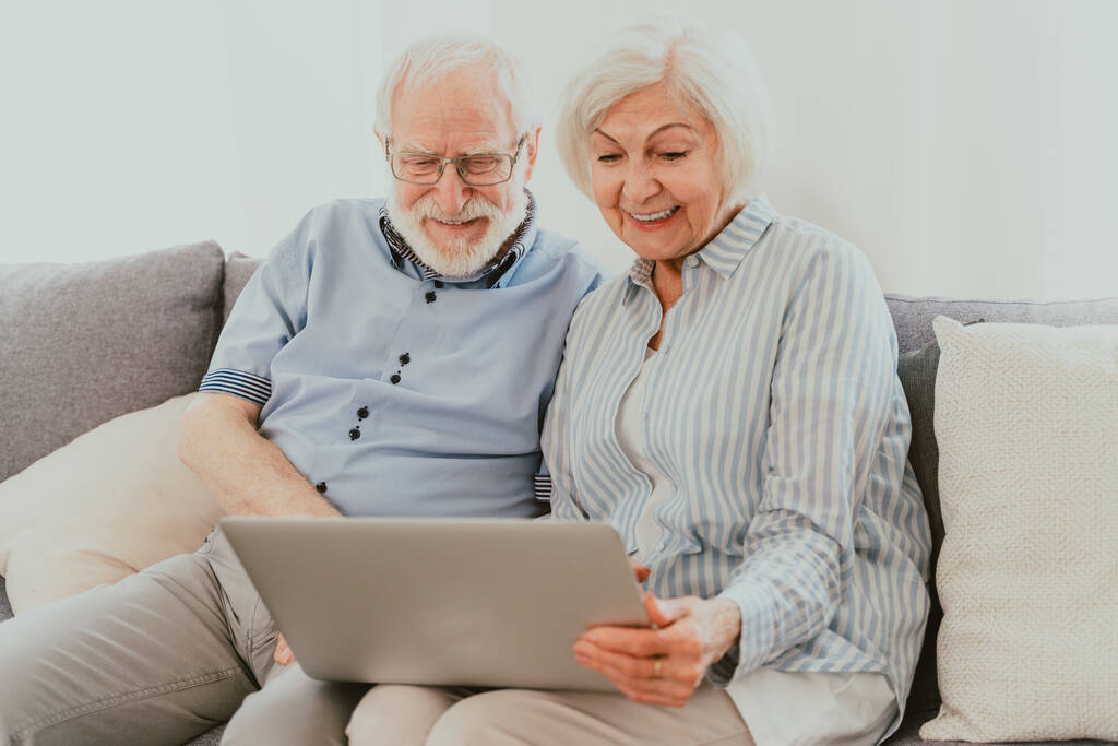 Ouderen paar winkelen online op internet met computer laptop thuis - Mooie gelukkige ouderen met behulp van pc en sociale netwerk apps - Foto, afbeelding