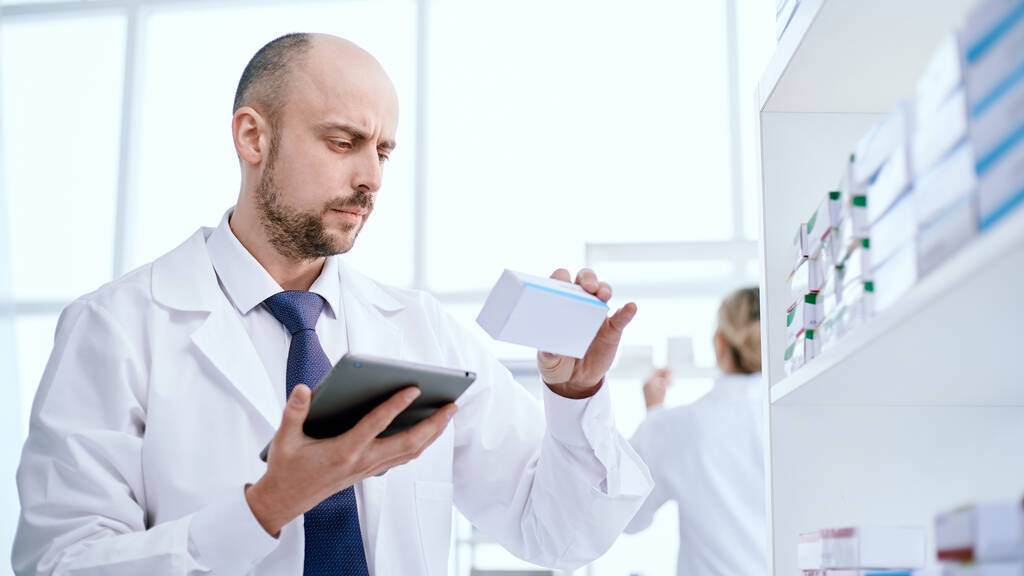 pharmacist with a digital tablet looking at a box of medicines. - Photo, Image
