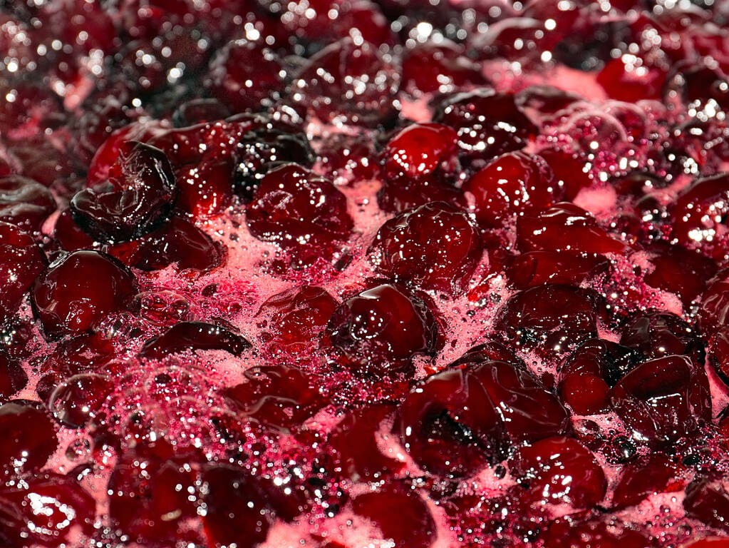 espuma y burbujas de aire en la superficie de la mermelada de cereza hirviendo al cocinar - Foto, imagen