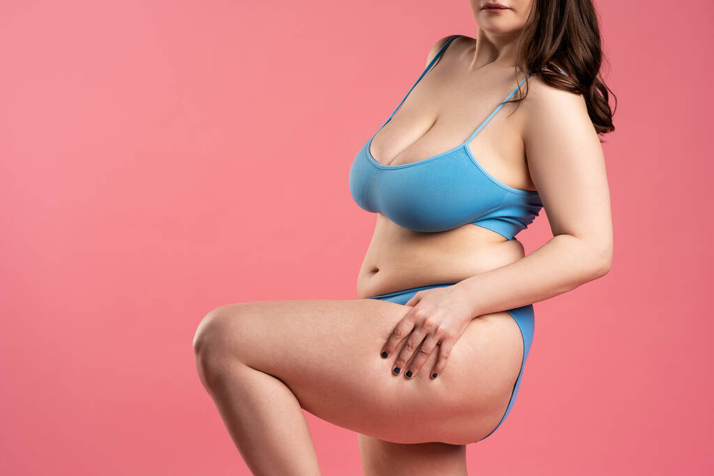 Fat woman with cellulite on thighs in blue underwear on pink background, body care concept, studio shot - Photo, Image