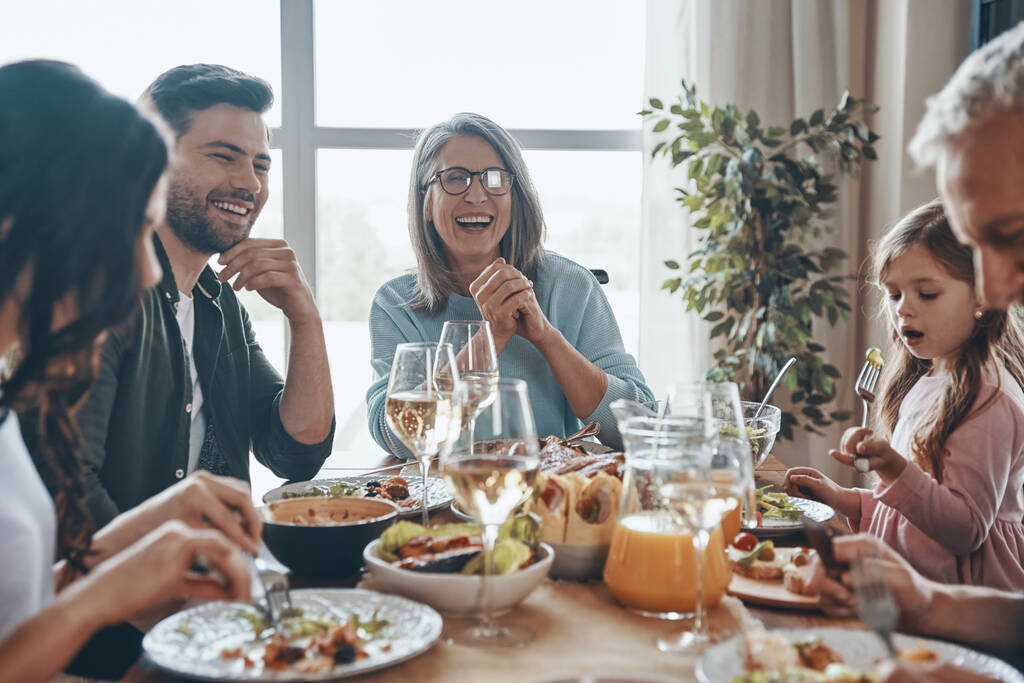 Szczęśliwa wielopokoleniowa rodzina komunikująca się i uśmiechnięta podczas wspólnej kolacji - Zdjęcie, obraz