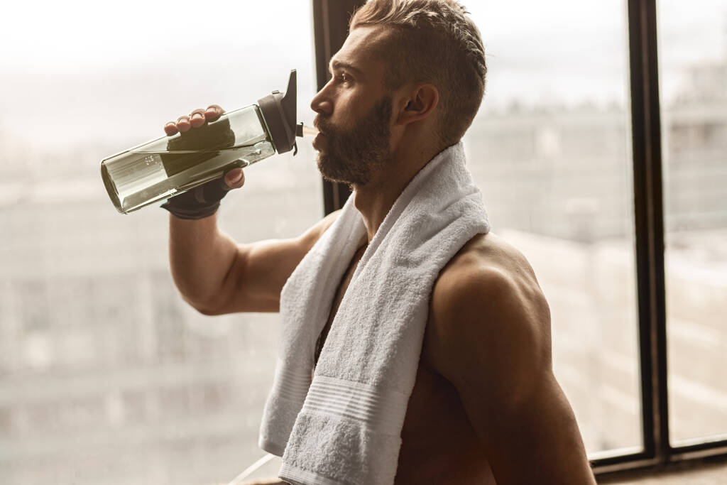 Hombre beber agua después de entrenar en el gimnasio - Foto, imagen