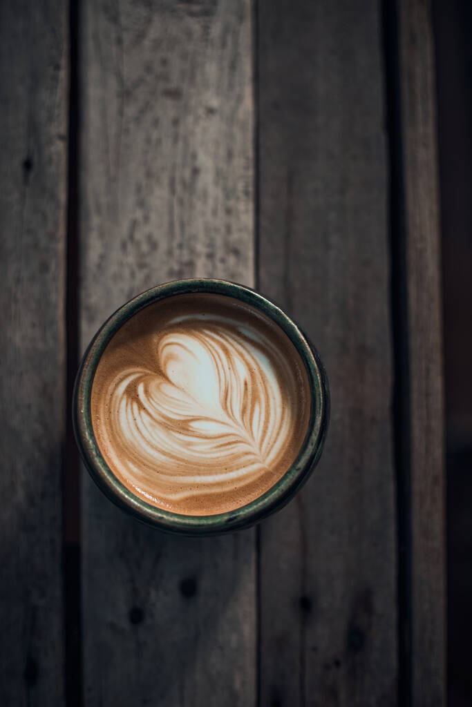 Taza selectiva del foco del café caliente del arte del latte en la mesa de madera, foco en espuma blanca - Foto, Imagen