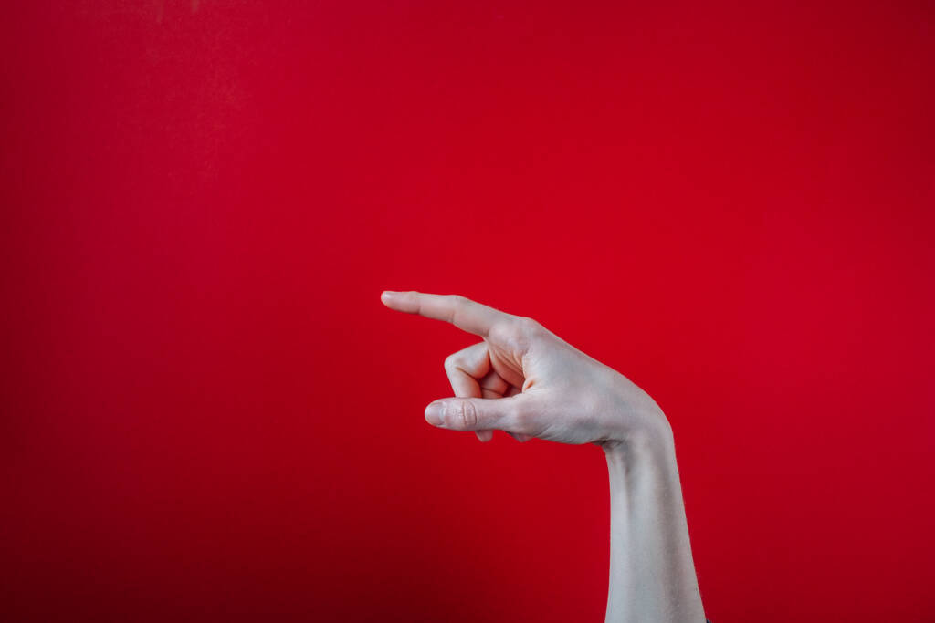 Un primo piano di una mano che punta il dito su uno sfondo rosso - Foto, immagini