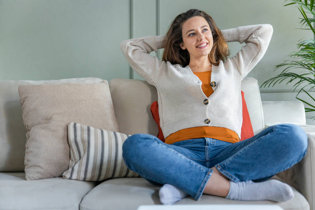 Молодая женщина отдыхает дома на диване, наслаждаясь выходными - Фото, изображение