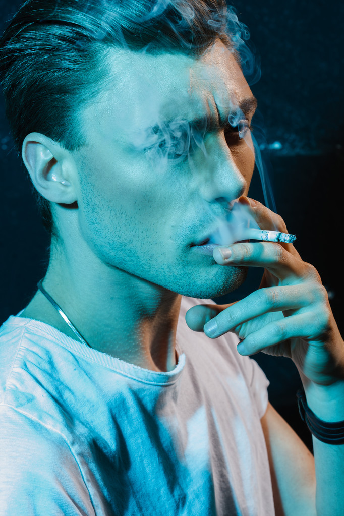 Красивый молодой человек курит сигарету
 - Фото, изображение
