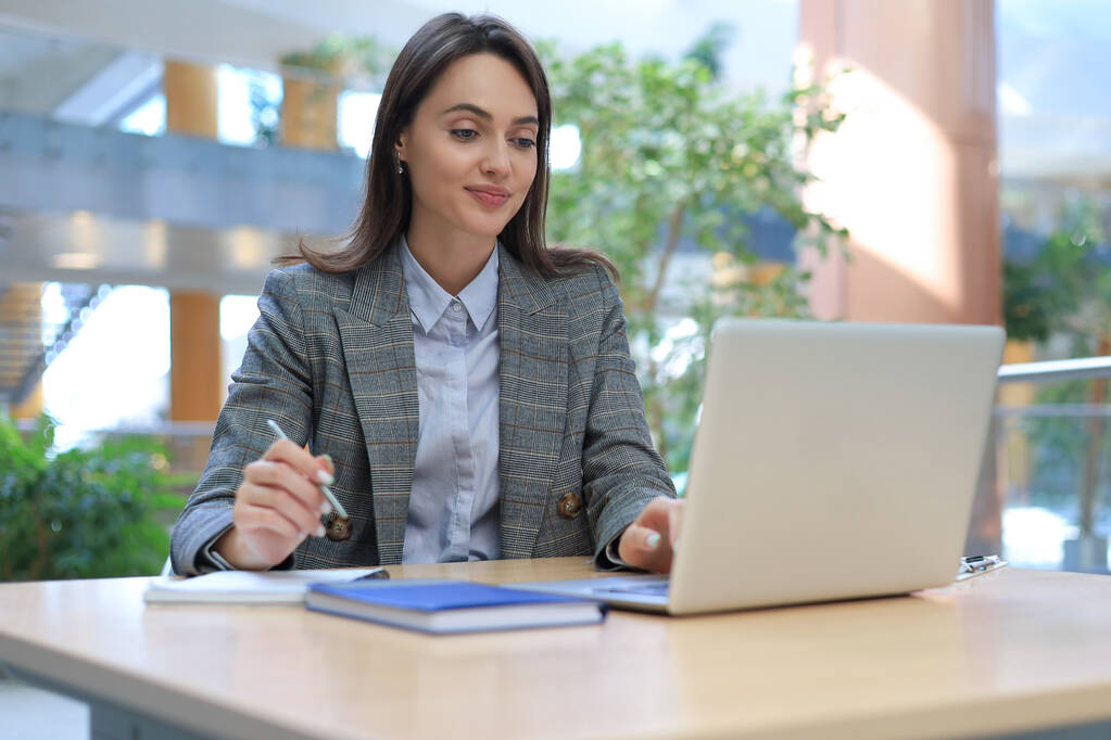 Портрет молодої брюнетки бізнес-леді, використовуючи ноутбук в офісі
 - Фото, зображення