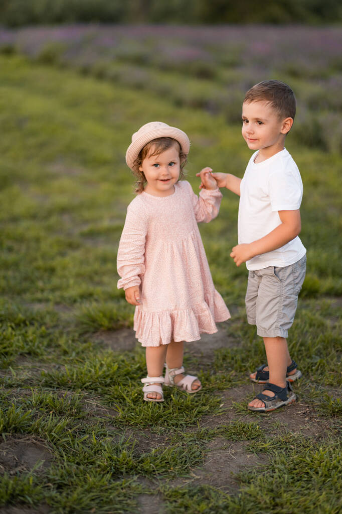 kisfiú és lány szórakozik a virágos mezőn - Fotó, kép